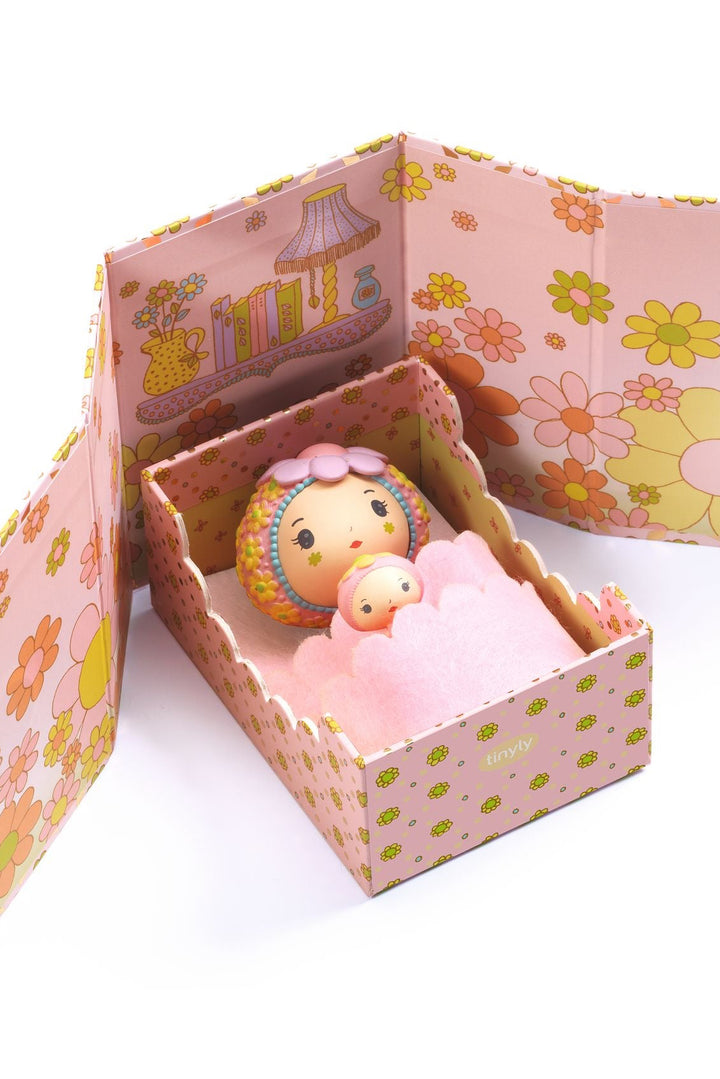 Decorative box with floral patterns containing a small figurine and pink plush toy on a white background