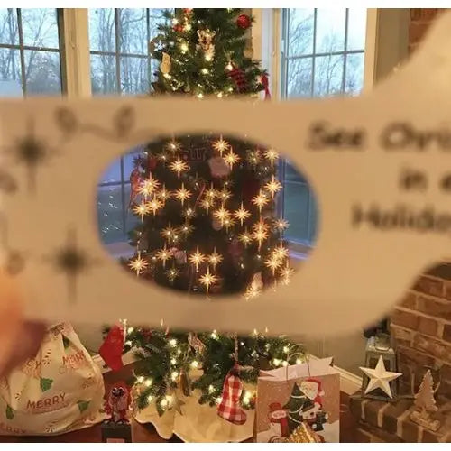 Decorated Christmas tree with lights and ornaments, held up to a window with a snowy view. Looking through 3-D Paper Glasses