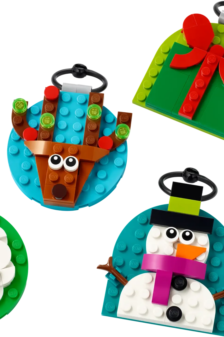 4 lego ornaments in bright colors with a Santa, snowman with a fuchsia scarf, reindeer with Christmas lights in its' antlers, and a green wrapped gift with a red bow. 