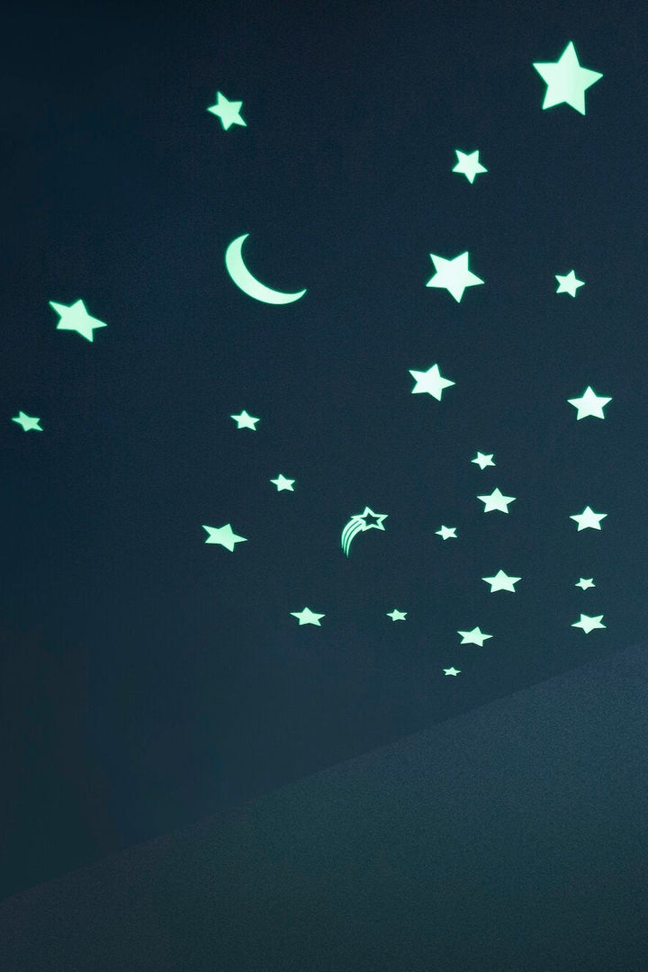 A collection of glow-in-the-dark stickers on a dark background, featuring various stars and a crescent moon shape.