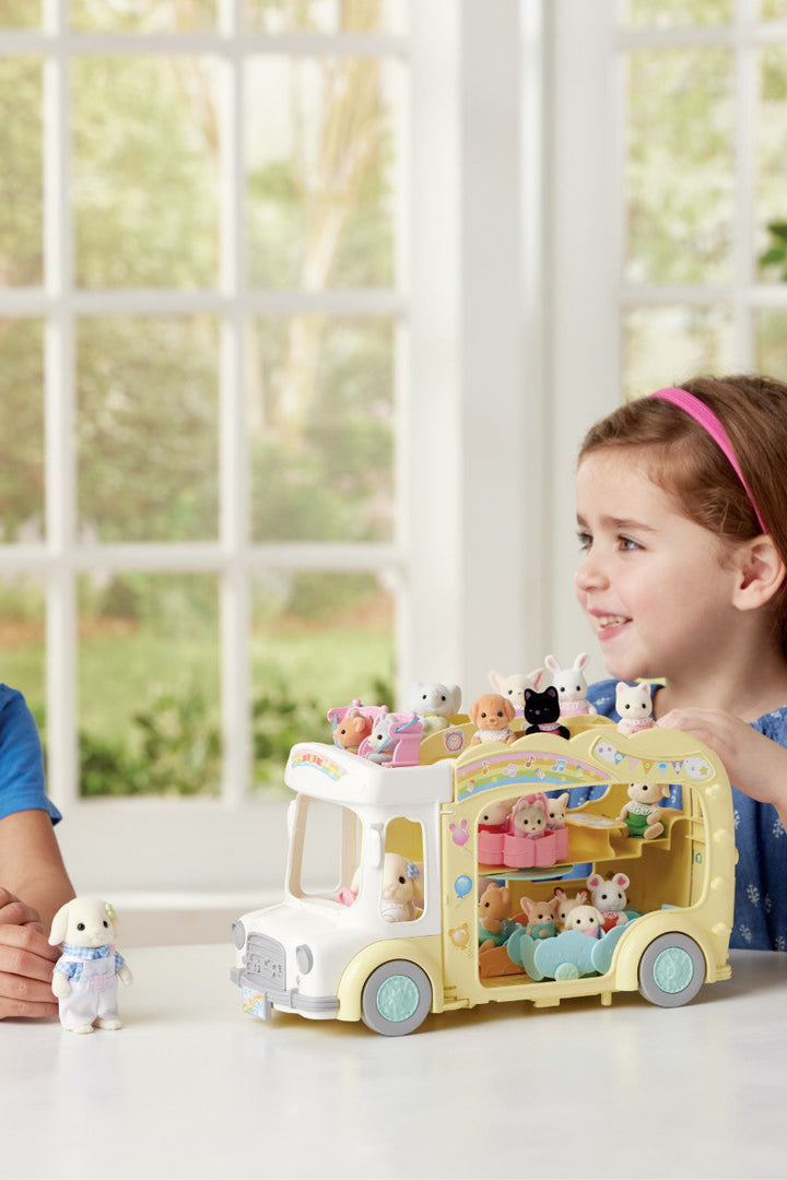 Two children playing with a toy ice cream truck and animal figures indoors.